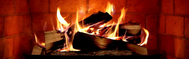 photo of inside of brick fire place with random piled logs and fire.