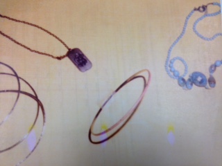 two thin gold bracelets and one orange bracelet found on her left wrist, and two necklaces around her nec